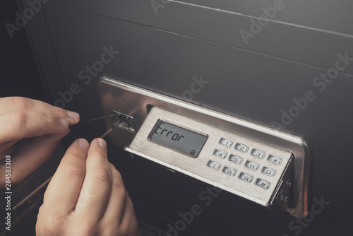 Close-up of Thief's hands attempting to Break Home Money Safe and perform Robbery.