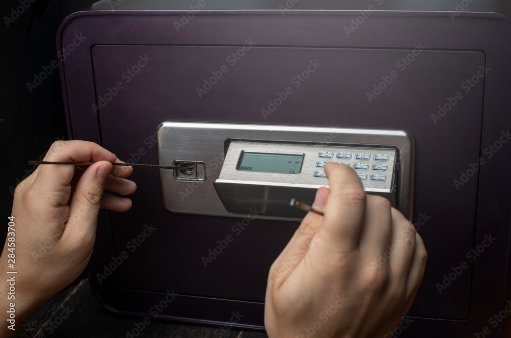 Close-up of Thief's hands attempting to Break Home Money Safe and perform Robbery. Close-up of Thief's hands attempting to Break Home Money Safe and perform Robbery.