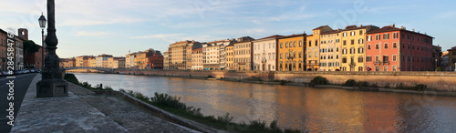 Panoramic view of Arno river with palazzo facades in Pisa, Italy, on a sunny evening