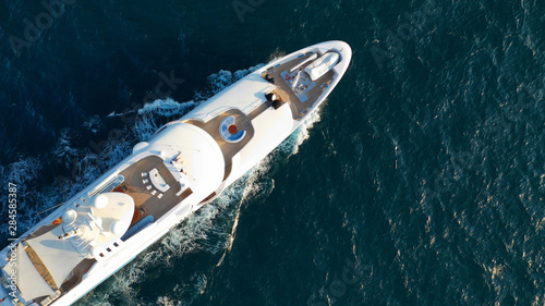 Aerial drone top view photo of luxury yacht, cruising in moderate speed in open sea with splash and wave on background © aerial-drone