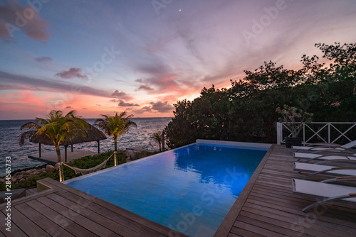 Sunset over the sea from a house and swimming pool © Gail Johnson