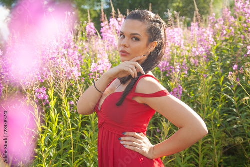 pretty mixrace brunette girl in red dress posing in pink nature flowers field photo