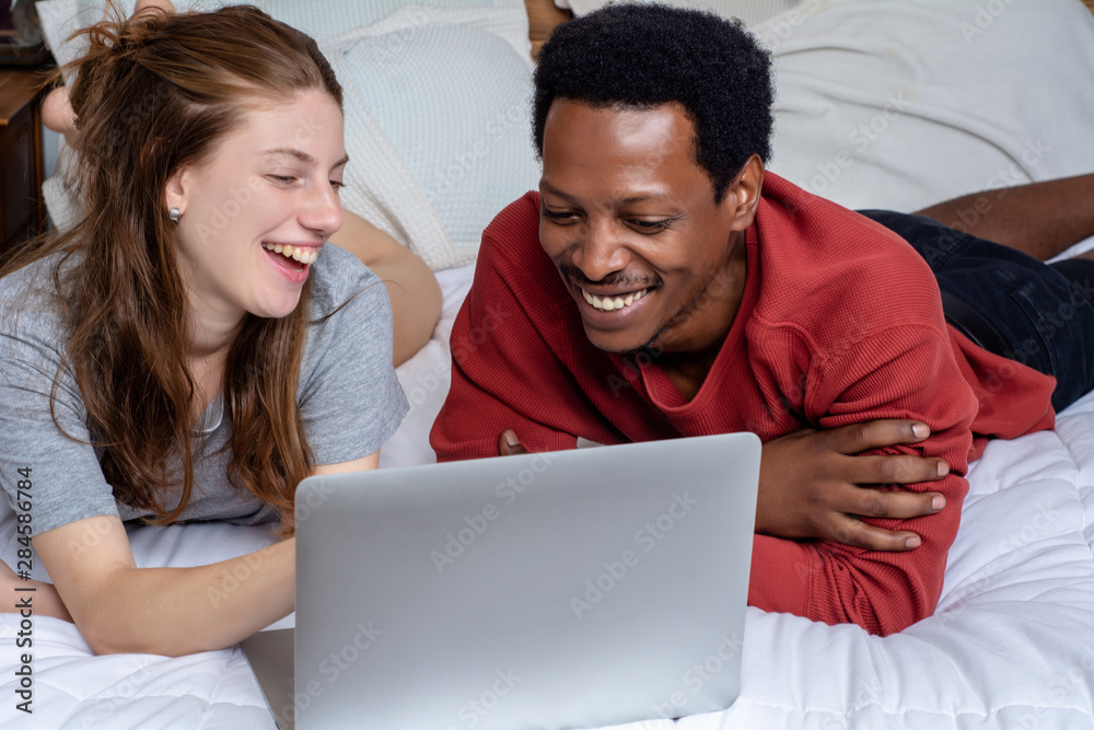 Young couple using laptop in a bed at home.