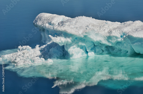 Frozen White Confection Iceberg with Reflection in Calm Ocean in Antarctica