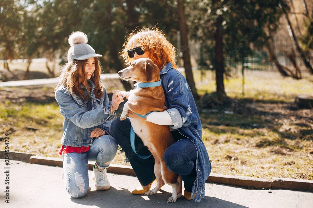 Beautiful girls in a park. Stylish women in a jeans jacket. Ladies with a dog. Mother with a daughter Beautiful girls in a park. Stylish women in a jeans jacket. Ladies with a dog. Mother with a daughter
