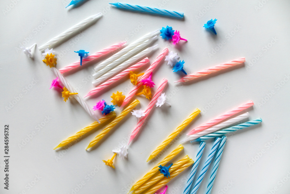 Festive bright colorful birthday candles scattered on white background. Yellow, pink, blue and white twisted candles. Birthday or anniversary celebration. Template for birthday or greeting card, print