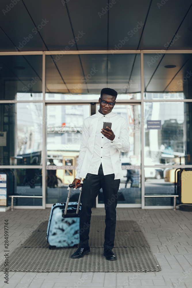 Fototapeta premium Handsome black man in a city. Businessman in a white shirt
