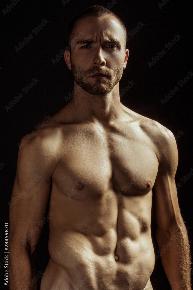 Handsome sport sexy stripped guy portrait for cosmetics and fitness drops on isolated black background