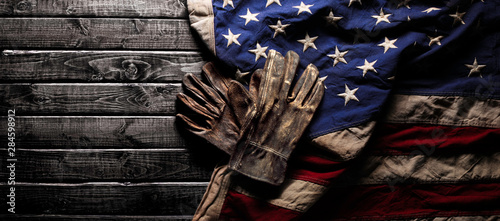 Fotografie, Obraz Old and worn work gloves on large American flag - Labor day background