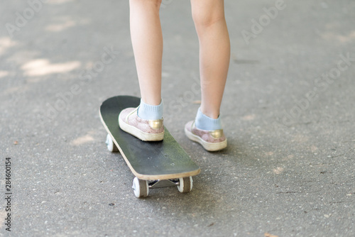 Legs of a little girl on a skateboard.