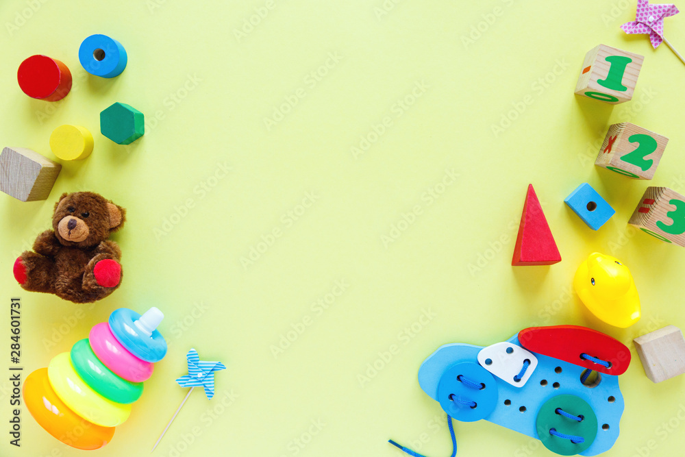 Obraz premium Kids toys: pyramid, wooden blocks, bear, train frame on colored background. Top view. Flat lay. Copy space for text
