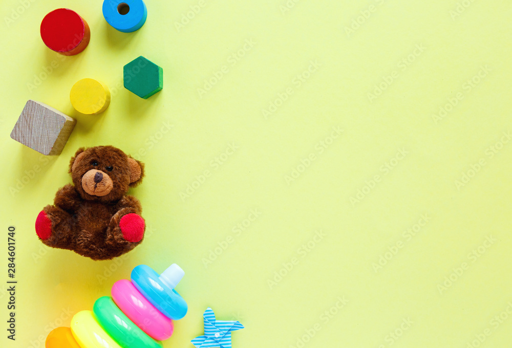Kids toys: pyramid, wooden blocks, bear, train frame on colored background. Top view. Flat lay. Copy space for text