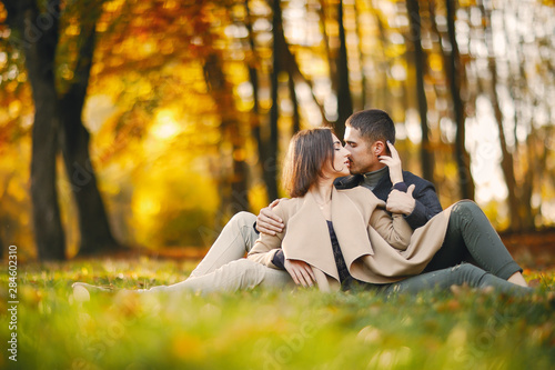 lovely couple sitting the park during autumn