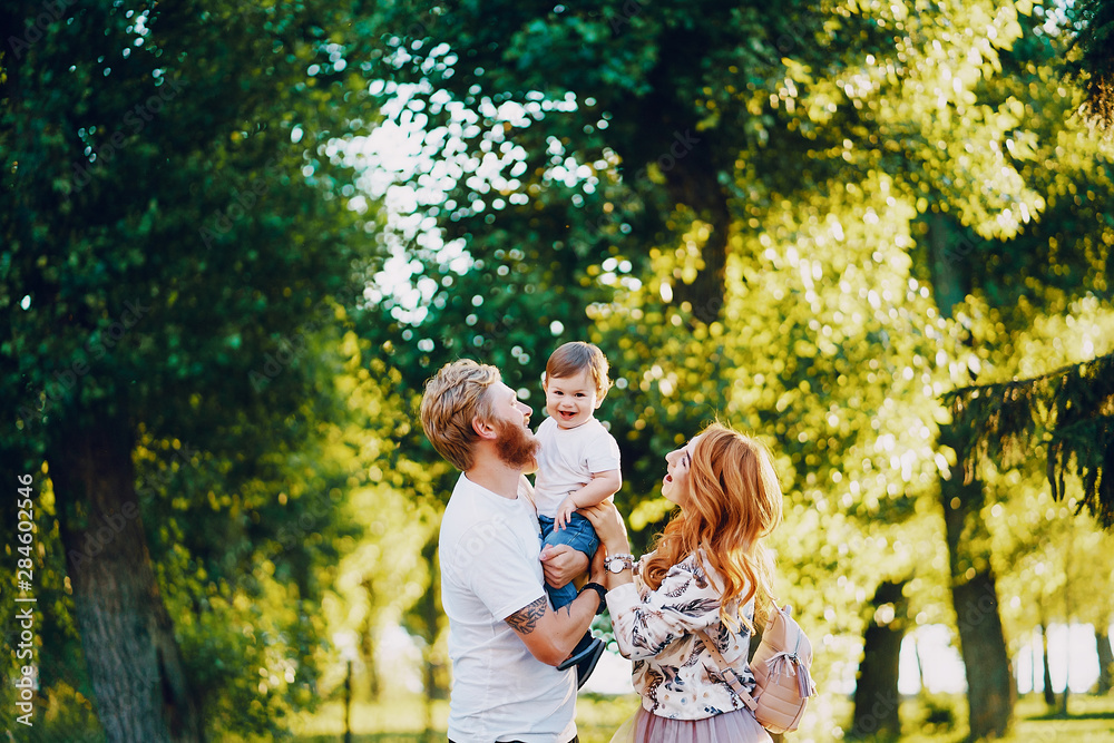 Beautiful red-haired woman with her husband and a wonderful son on a summer park