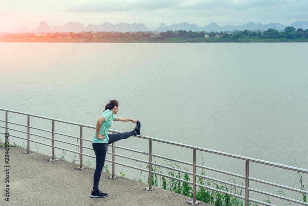 Woman is relax standing after run with a view of the river in the morning.
