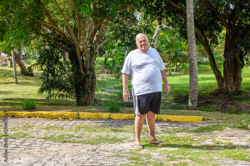 Fat old man walks exercises nature park