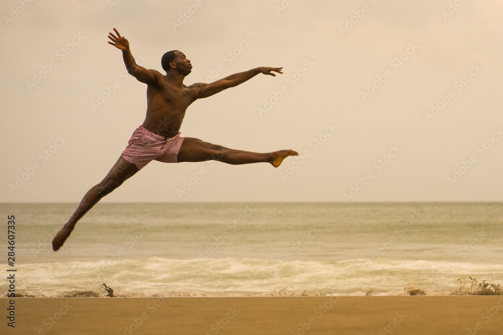 contemporary dance choreographer doing ballet beach workout . young attractive and athletic black African American man dancing on sunrise jumping elegant contemporary dance choreographer doing ballet beach workout . young attractive and athletic black African American man dancing on sunrise jumping elegant