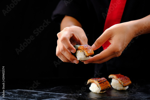 Hands of japanese chef holding unagi sushi. photo
