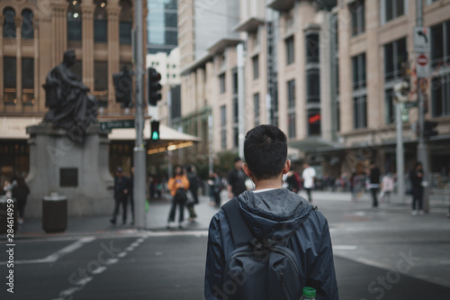 Young man with headphones in waiting to cross the road in the city.