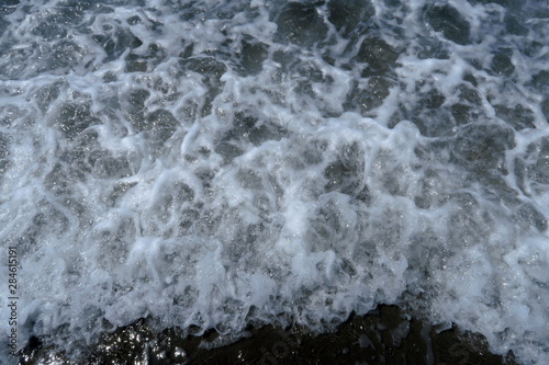 Vagues et écumes au bord de l'eau sur a plage.