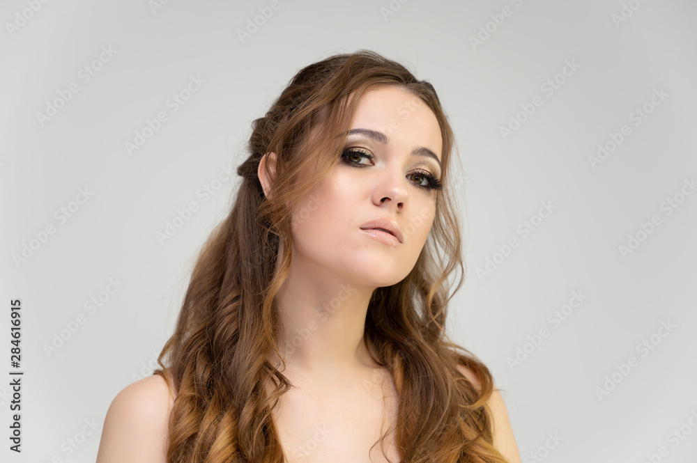 Close-up photo portrait of a pretty brunette woman girl with long beautiful curly hair on a white background. Standing in front of the camera Close-up photo portrait of a pretty brunette woman girl with long beautiful curly hair on a white background. Standing in front of the camera