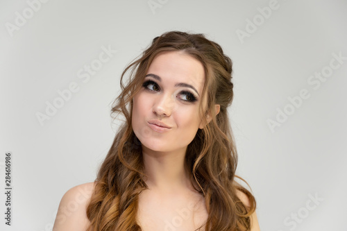 Close-up photo portrait of a pretty brunette woman girl with long beautiful curly hair on a white background. Standing in front of the camera