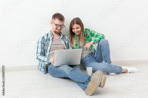 Charming young woman and a smiling man are watching online stores using a laptop to buy plumbing in a new apartment. Housewarming and repair concept.