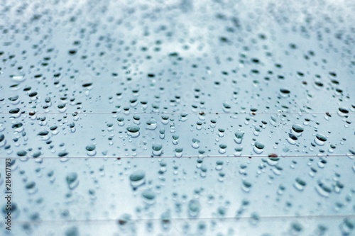 In selective focus rain droplets on a car mirror with blue tone for background texture