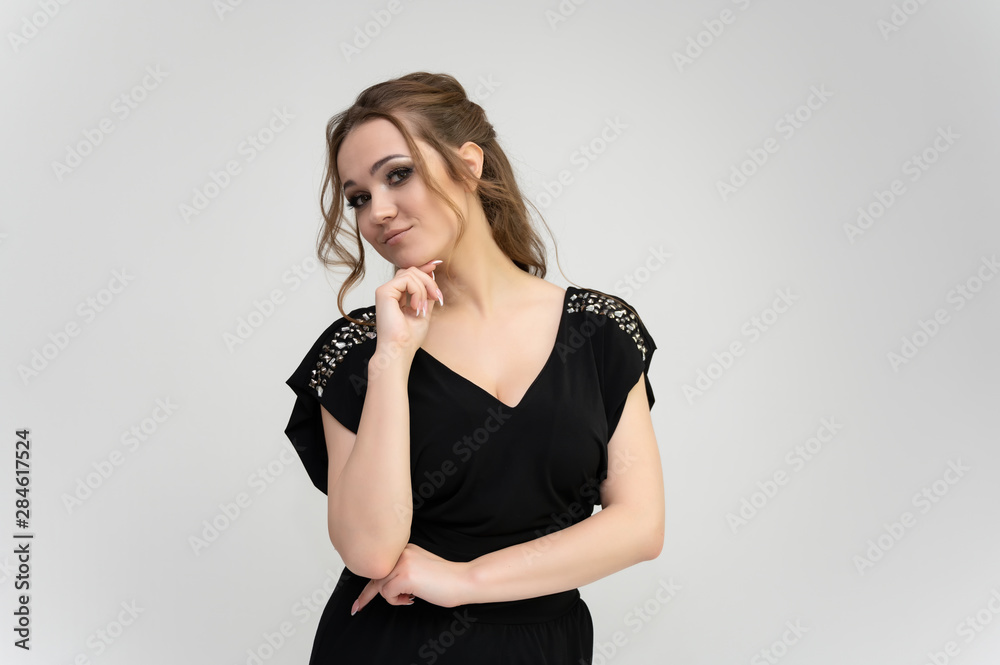 Photo waist-length portrait of a pretty brunette woman girl with long beautiful curly hair on a white background in a black dress. Talking in different poses. Standing facing the camera. Photo waist-length portrait of a pretty brunette woman girl with long beautiful curly hair on a white background in a black dress. Talking in different poses. Standing facing the camera.