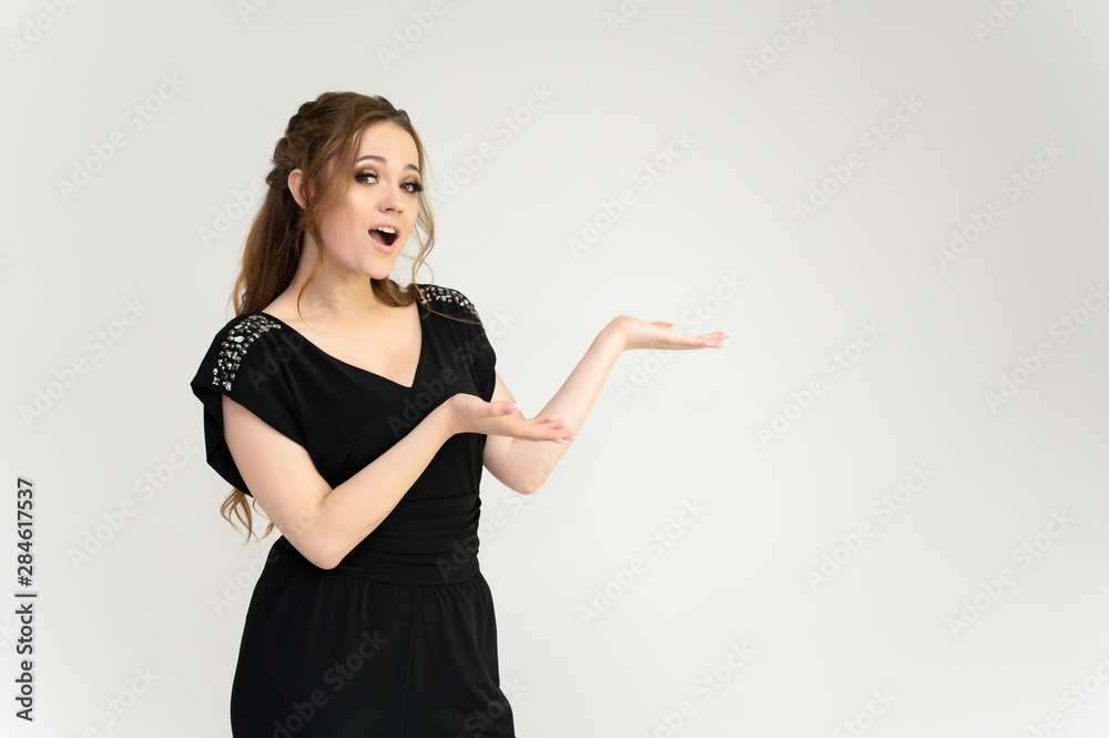 Photo waist-length portrait of a pretty brunette woman girl with long beautiful curly hair on a white background in a black dress. Talking in different poses. Standing facing the camera.