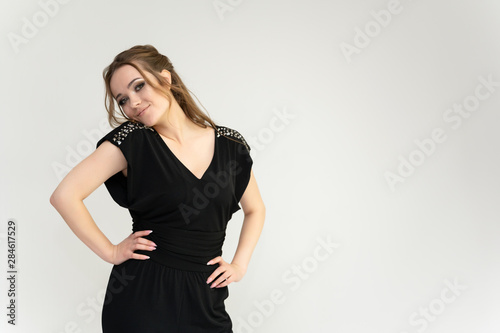 Photo waist-length portrait of a pretty brunette woman girl with long beautiful curly hair on a white background in a black dress. Talking in different poses. Standing facing the camera.