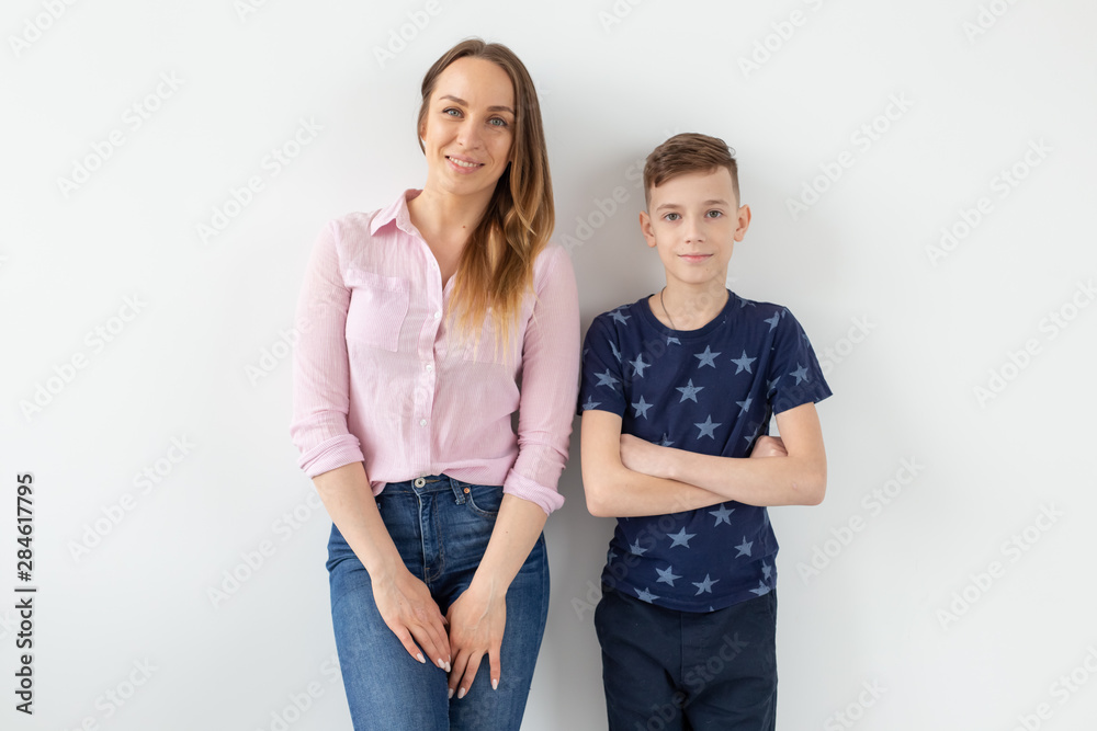 Good-looking single-parent mom and teen son on white background. Cohesion, friendship and family relations. Good-looking single-parent mom and teen son on white background. Cohesion, friendship and family relations.