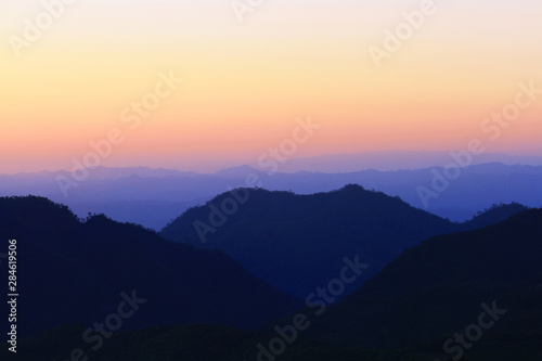 Sunset in sky and cloud, beautiful colorful twilight time with silhouette of mountain.