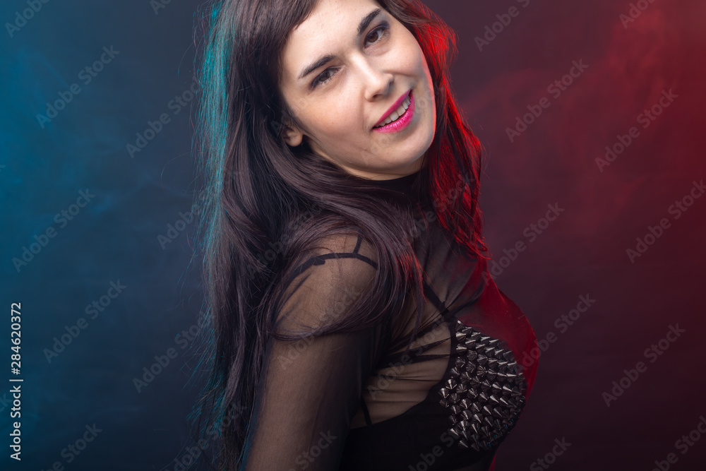 Alluring young beautiful brunette woman in a provocative dress posing on a dark background. Concept of seduction and sexual attractiveness. Alluring young beautiful brunette woman in a provocative dress posing on a dark background. Concept of seduction and sexual attractiveness.