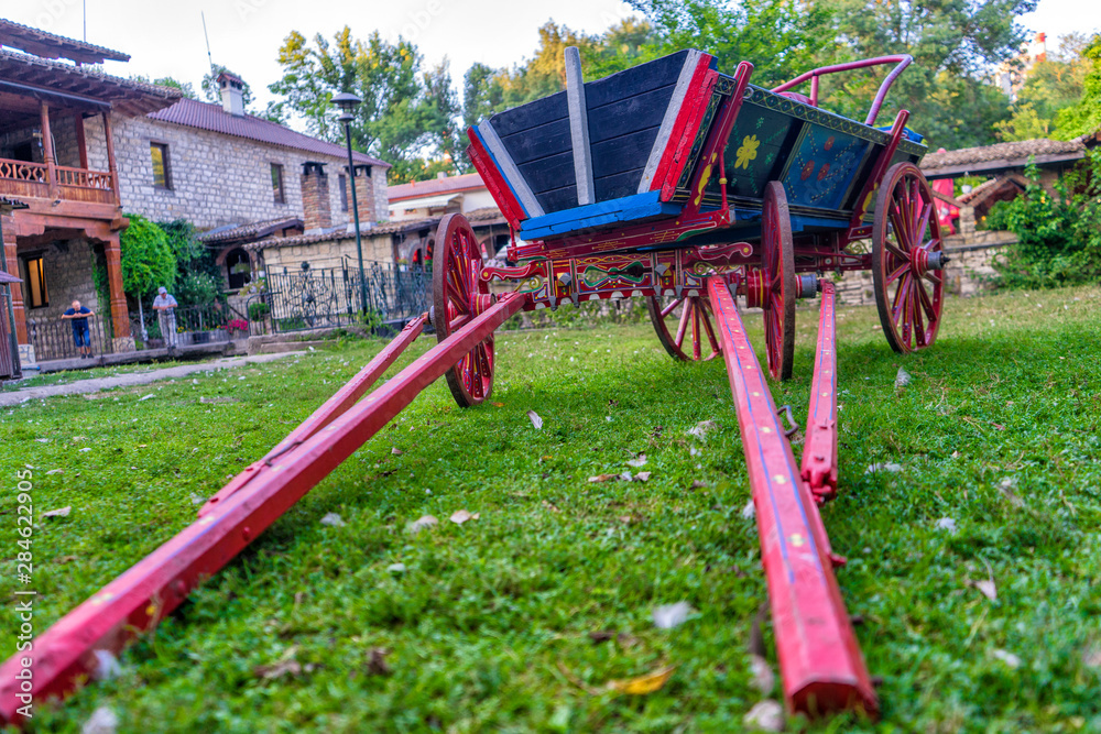 Cart on green grass in the background of houses. Cart without a horse. Cart on green grass in the background of houses. Cart without a horse.