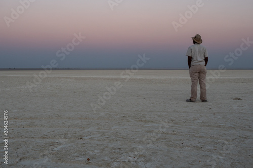 Dusk in Makgadikgadi Salt Pan - Black Man Gazing at Horizon photo