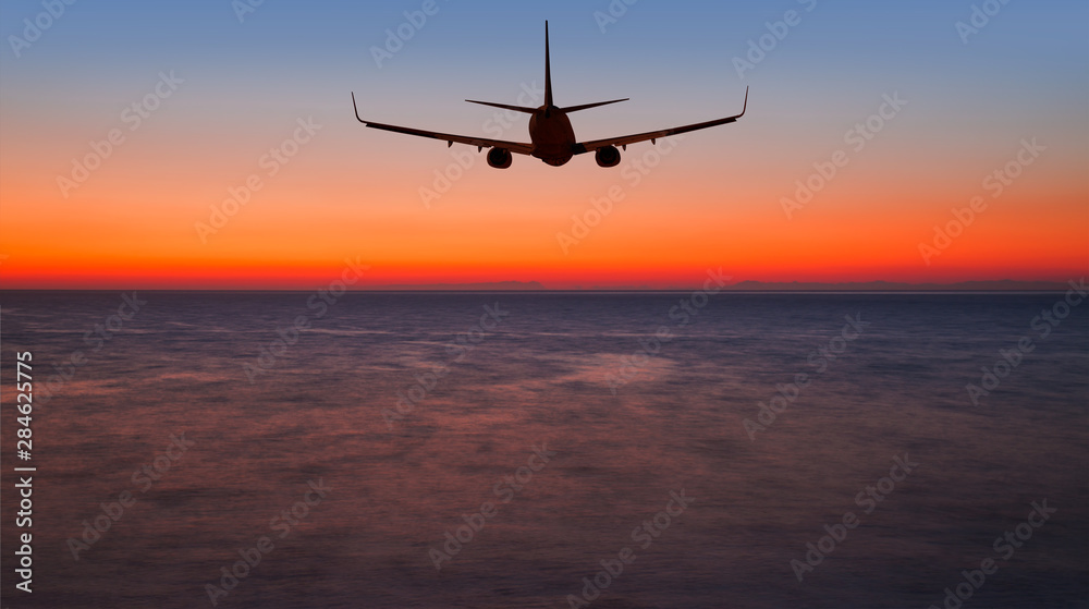 Airplane flying above tropical sea at sunset Airplane flying above tropical sea at sunset