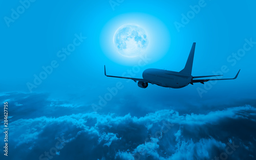 Fototapeta Naklejka Na Ścianę i Meble -  Commerical passenger airplane in the storm clouds - Night sky with moon in the clouds 