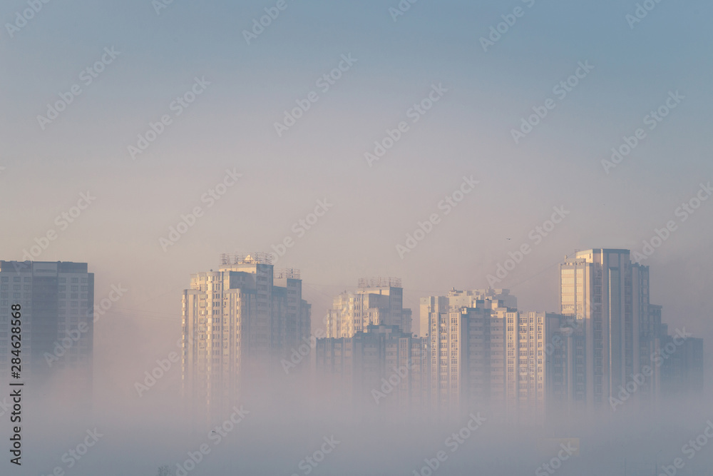 Dreamy city view. Modern residential buildings sticking out from the morning fog. Kyiv. Ukraine.