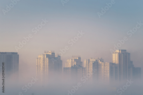 Dreamy city view. Modern residential buildings sticking out from the morning fog. Kyiv. Ukraine.