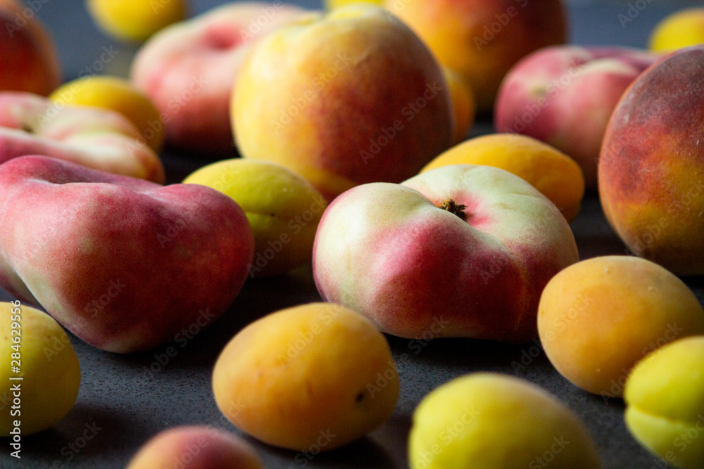 Apricots and peaches on dark texture surface. Close up of fresh summer fruits.