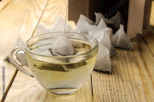 cup with tea and tea bag pyramid. close-up. on a wooden table. to make tea