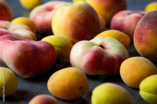 Apricots and peaches on dark texture surface. Close up of fresh summer fruits.