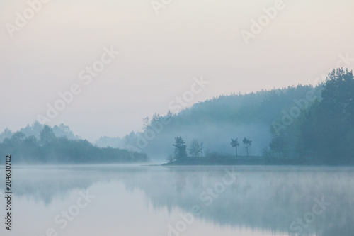 Grey fog over lake in rural area. Morning landscape. Fall concept