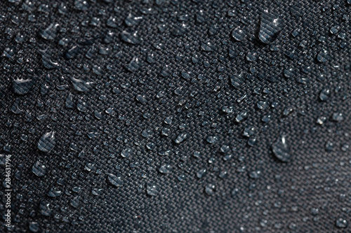 Фотография dark gray waterproof hydrophobic cloth closeup with water drops selective focus