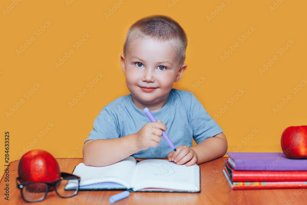 Little boy painting and doing homeworks on his desk, inspiration concept. back to school on yellow background Little boy painting and doing homeworks on his desk, inspiration concept. back to school on yellow background