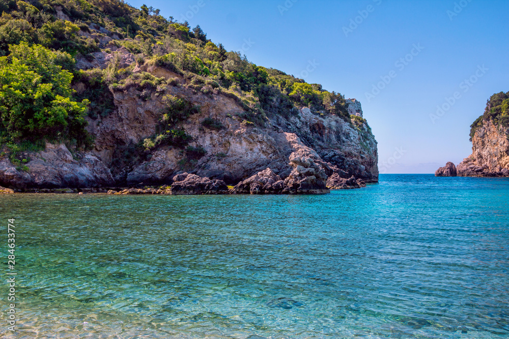 Beautiful landscape with sea, mountain and cliffs in a blue crystal clear water, green trees and bushes. Corfu Island, Greece. 