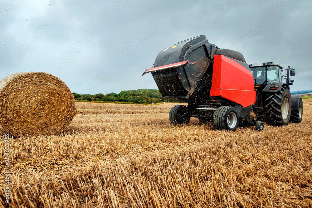 Obraz premium farmer in fields making straw bales