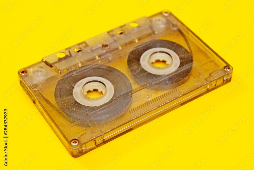 Old transparent audio cassette located on a yellow background Old transparent audio cassette located on a yellow background