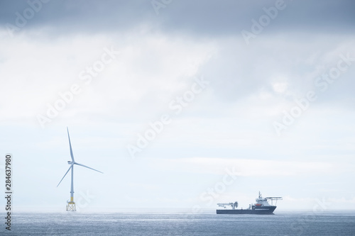 Ship on horizon under dark grey sky during a sea storm